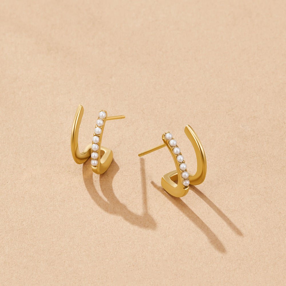 18K Gold & Pearl Claw Earrings, pair of gold earrings lying on a beige surface, with
