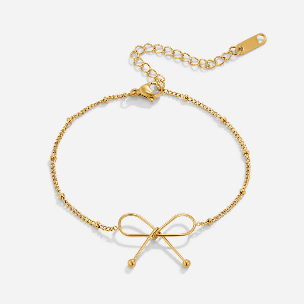 Anika Gold Bow Bracelet, flat lay of a gold bow bracelet with a beaded chain and extender