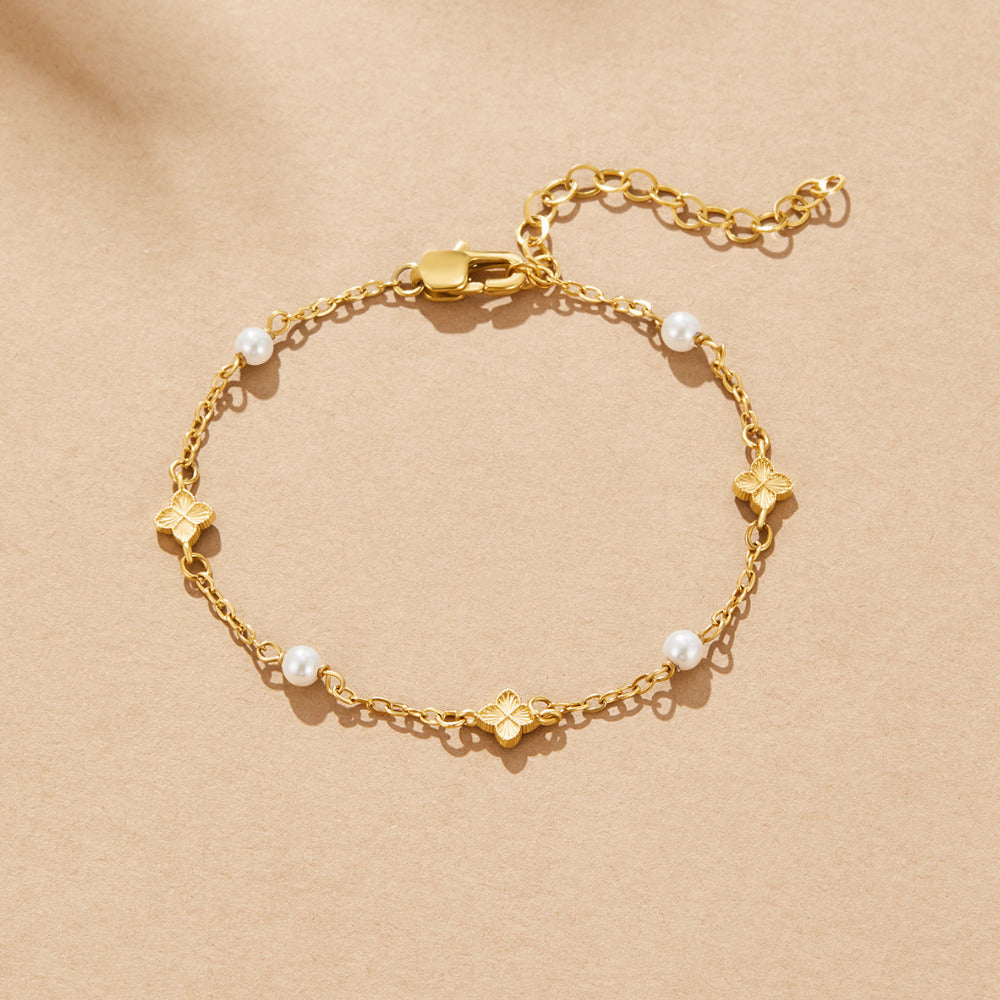 Camila Petal Bracelet, laid flat on beige paper, gold chain with pearls and clover charms