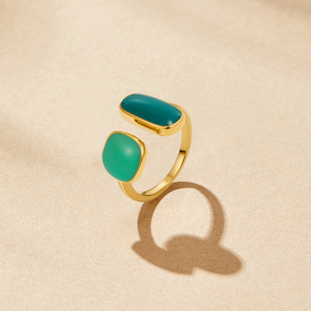 Green Willow Wrap Ring, open gold ring with two teal and green stones on beige surface
