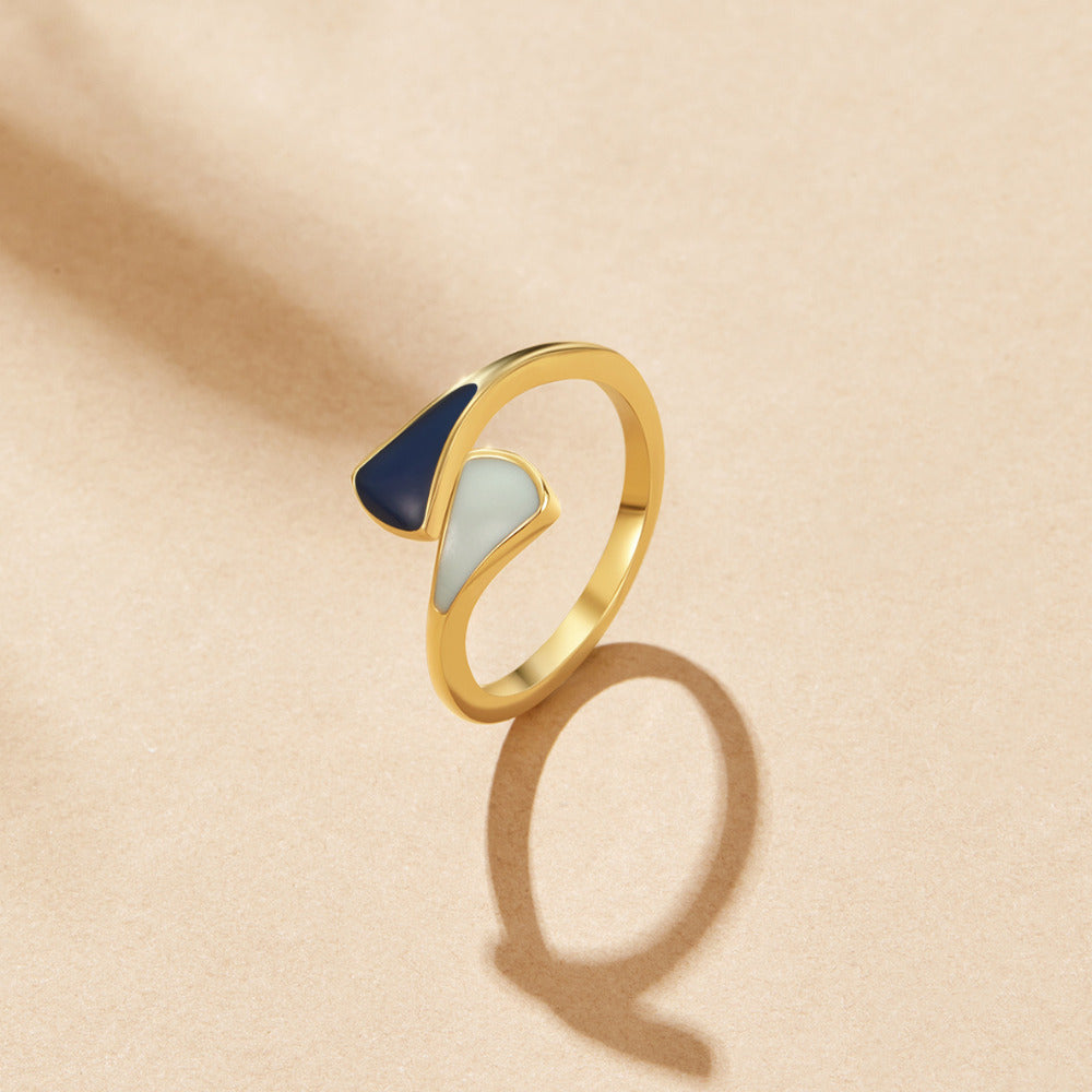 Safira Blue Dream Ring, open gold ring with navy and pale green enamel panels on beige surface