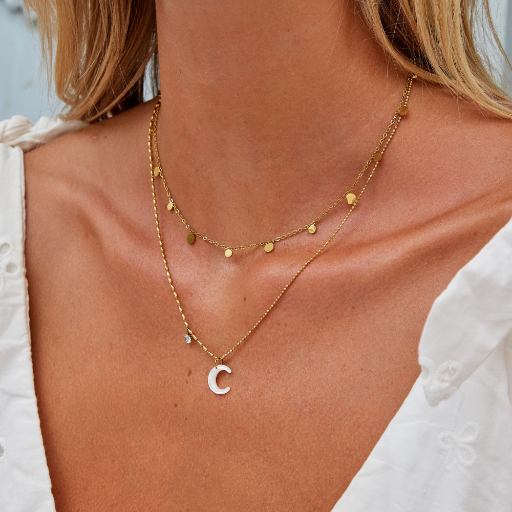 White Crescent Moon Necklace, worn on a neck with a white top, layered with a gold disc chain