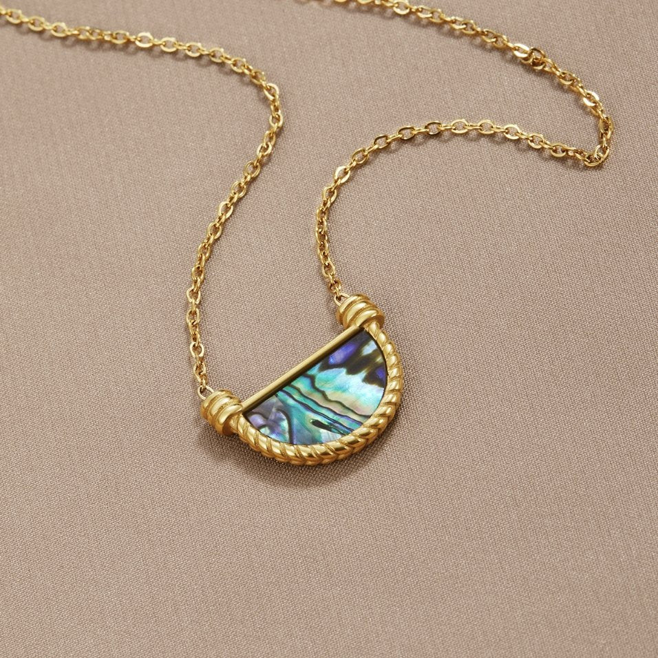 Amalfi Turquoise Shell Necklace, laid flat on a taupe fabric, gold chain with half-moon shell
