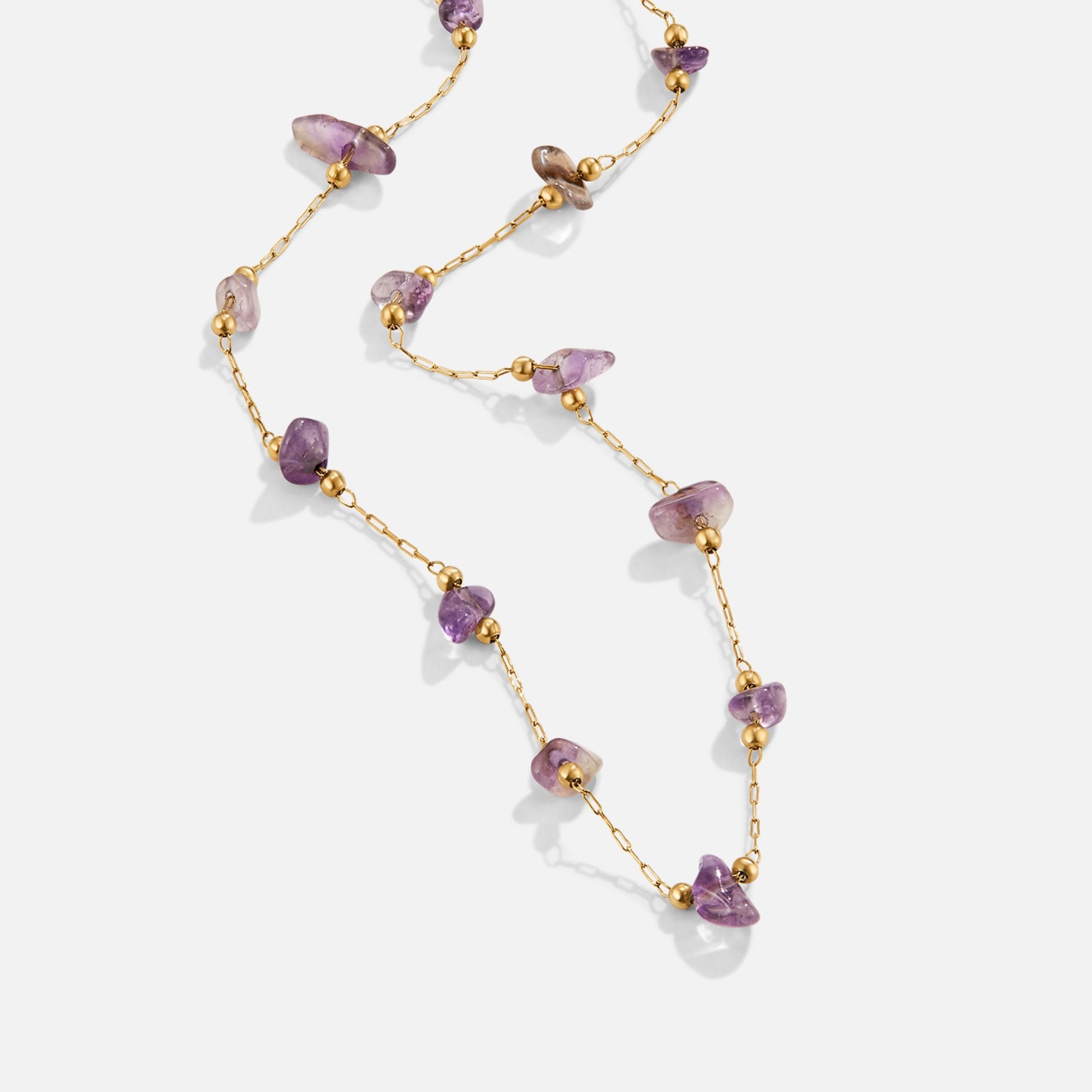 Amethyst Crystal Bead Necklace, laid out diagonally on white, gold chain with purple stones