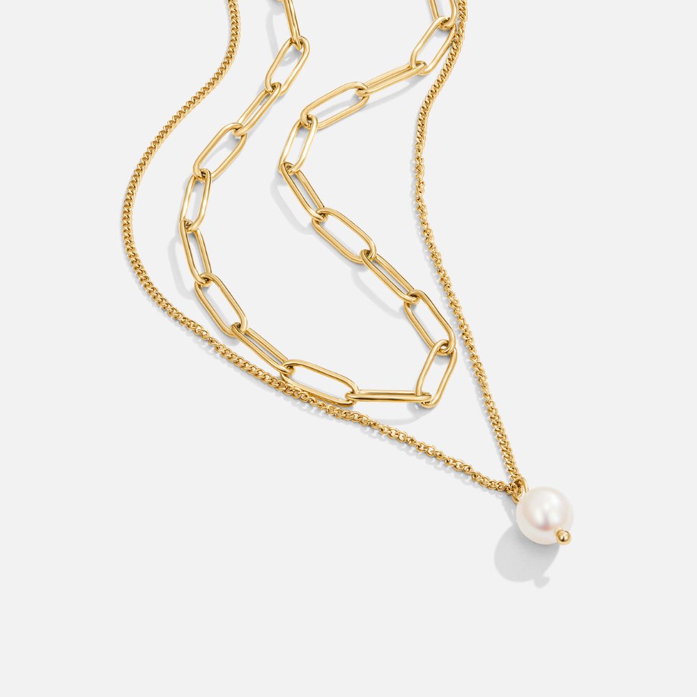 Angela Pearl Gold Necklace, layered gold chains on a plain background, with a pearl pendant