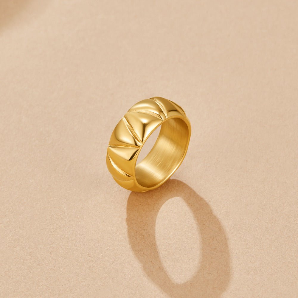 Anika Chunky Gold Ring, standing upright on a beige surface, gold ring with chevron grooves