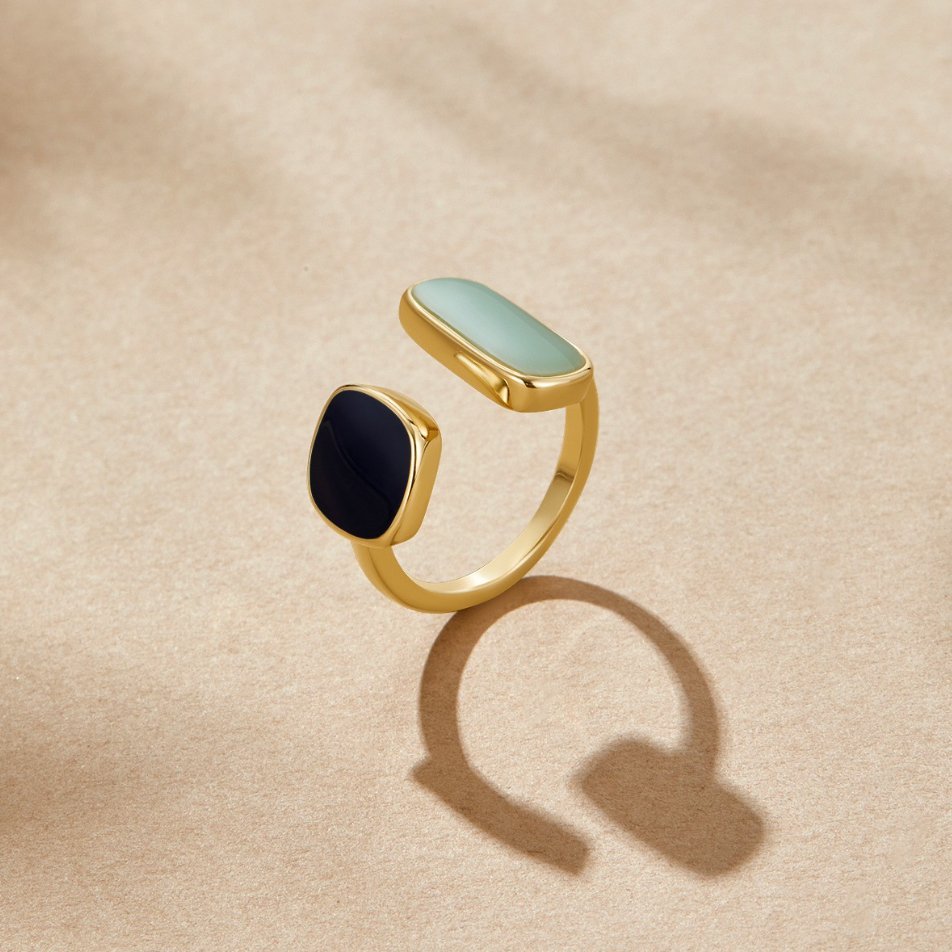 Aquamarine Wrap Ring, open gold ring with mint and black stones, on beige surface