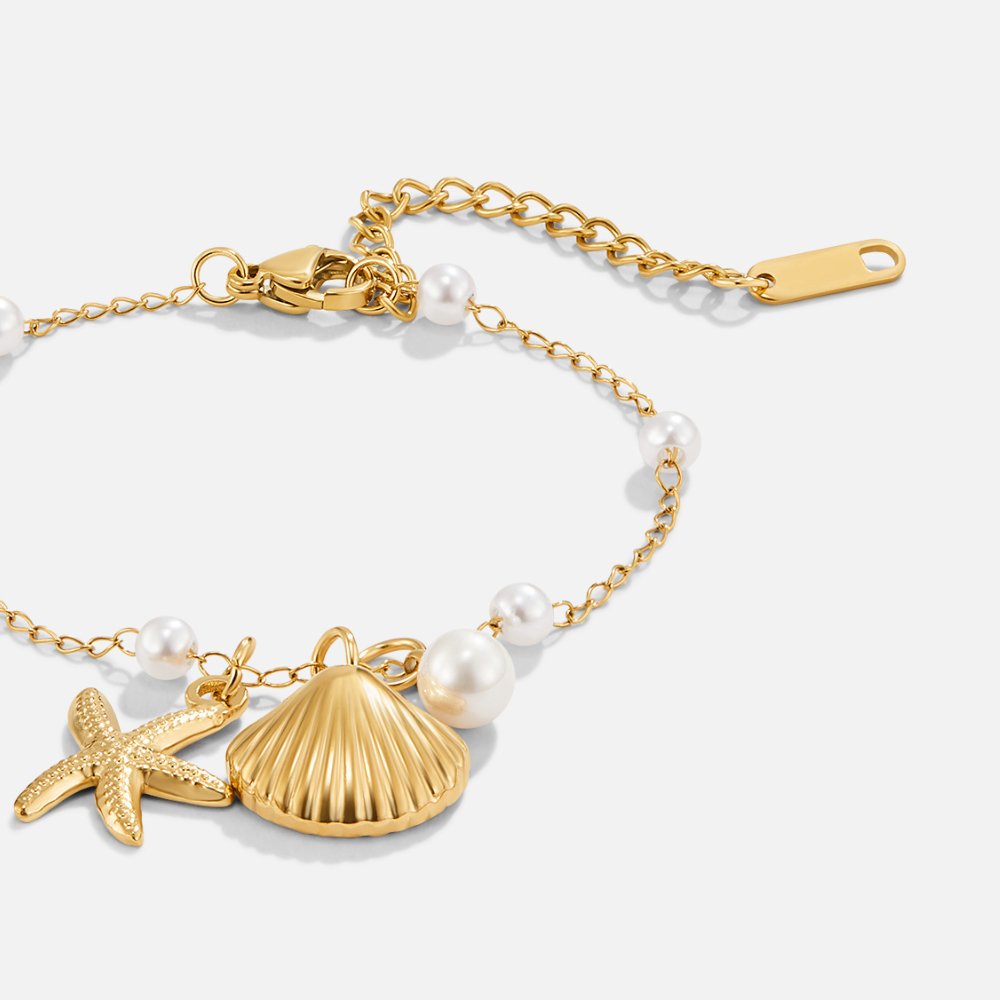 Aria Shell Charm Bracelet, flat close-up of gold starfish and ribbed shell charms on pearl chain