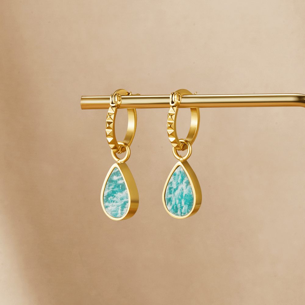Astoria Green Stone Hoop Earrings, hanging from a gold bar on a beige backdrop, teal teardrop charms