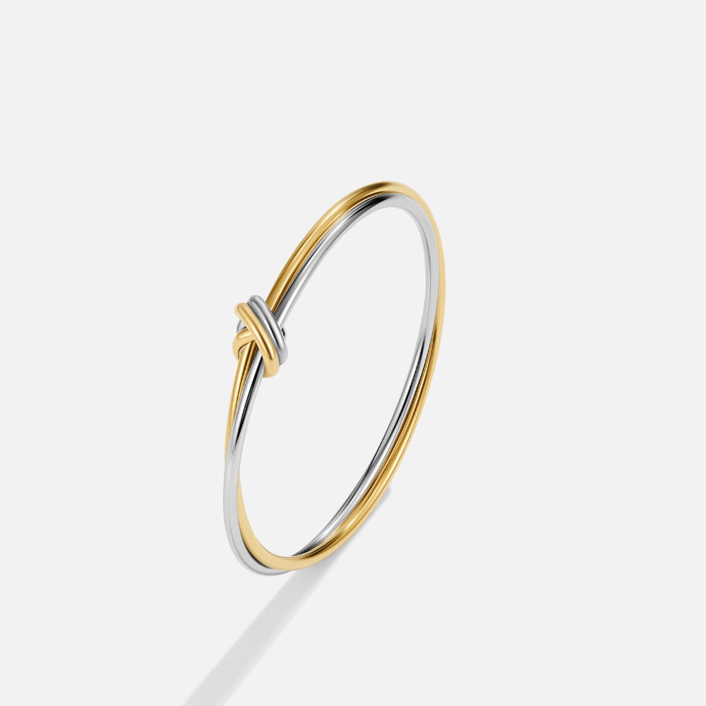 Ava Two-Toned Twisted Bangle, standing upright on a light grey background, gold and silver
