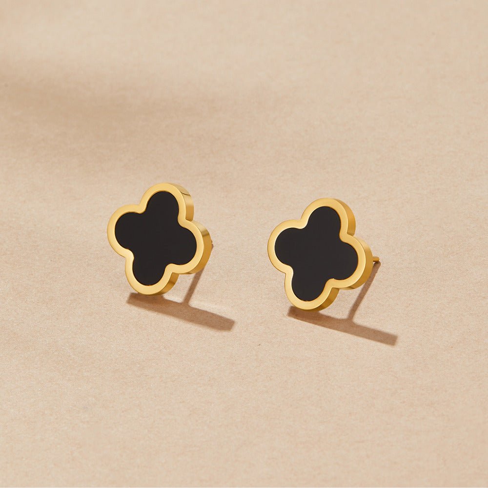 Black Clover Stud Earrings, a pair of studs on a beige surface, black clover centres with gold rims