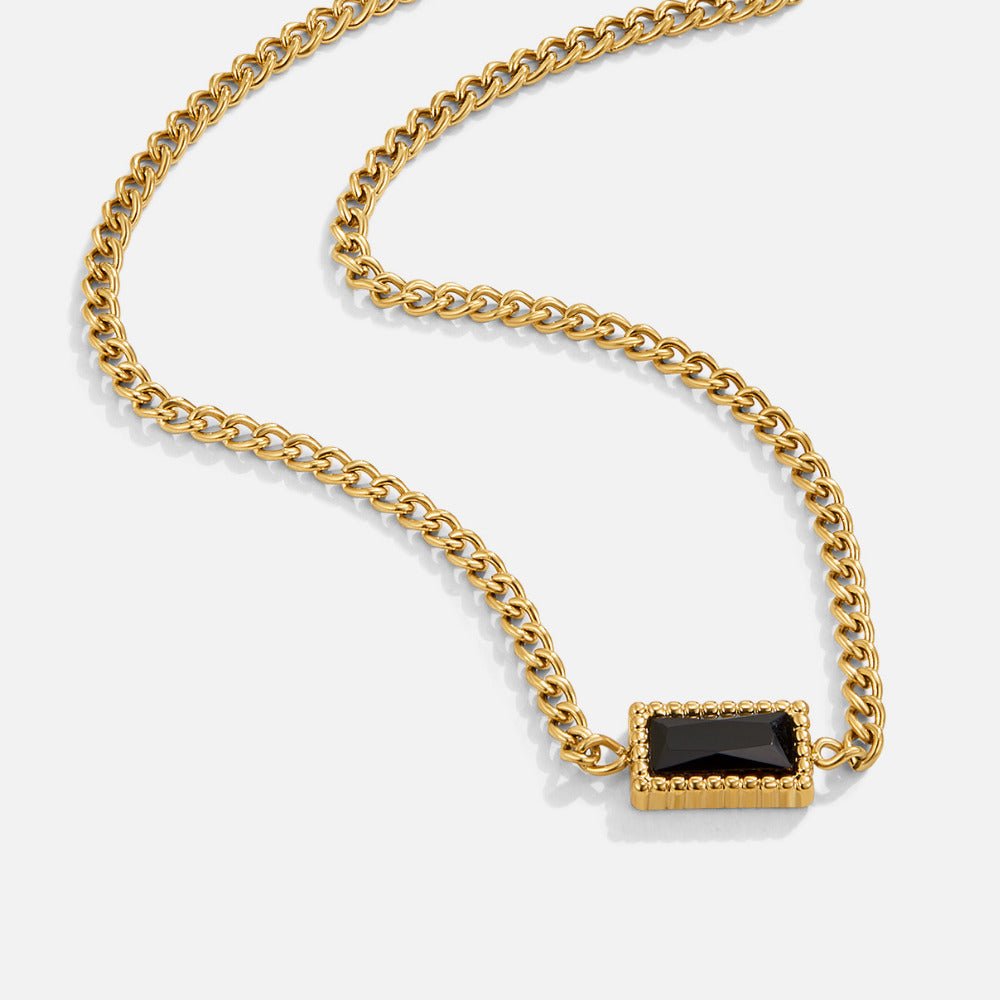 Black Onyx Pendant Necklace, gold curb chain necklace laid flat, with a black baguette stone pendant