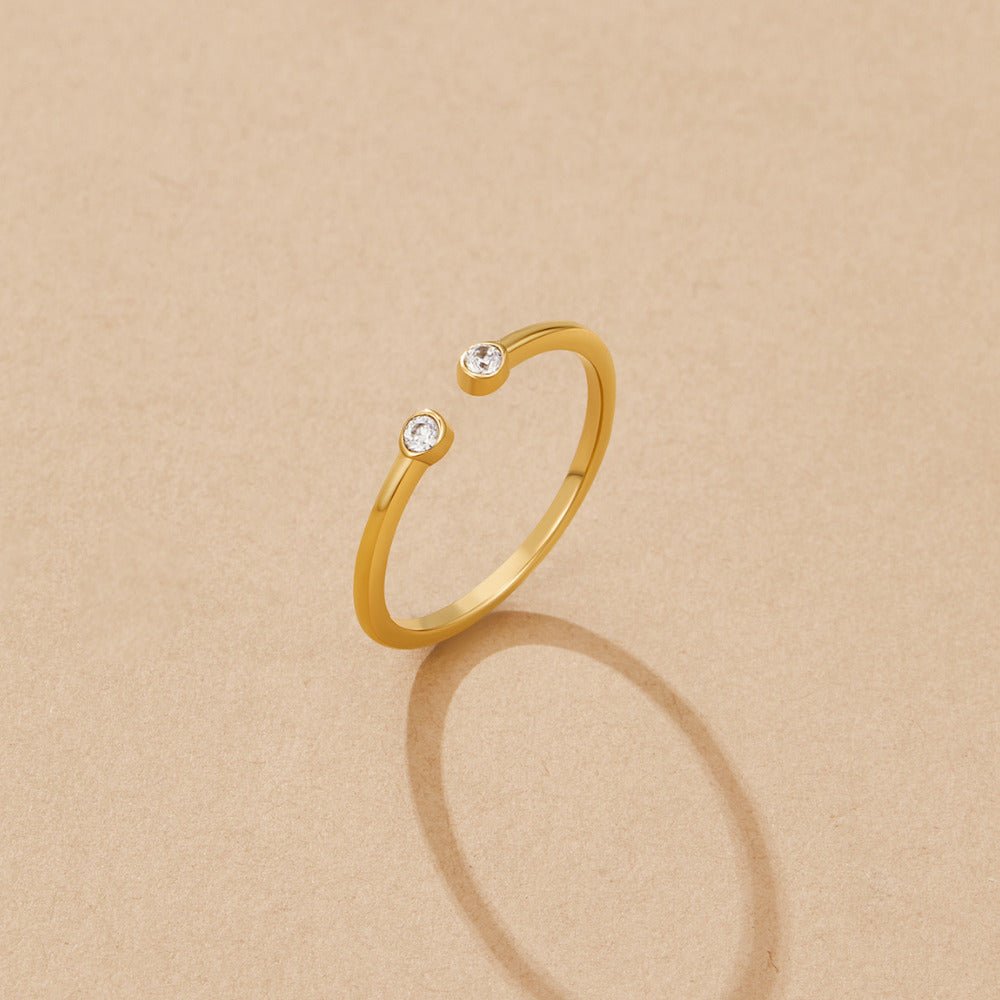 Cali Gold Crystal Ring, open gold band with a crystal at each end, on beige surface