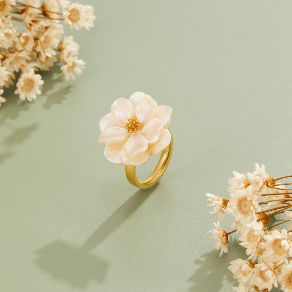 Camelia Bloom Ring, floating on a sage backdrop beside dried white flowers