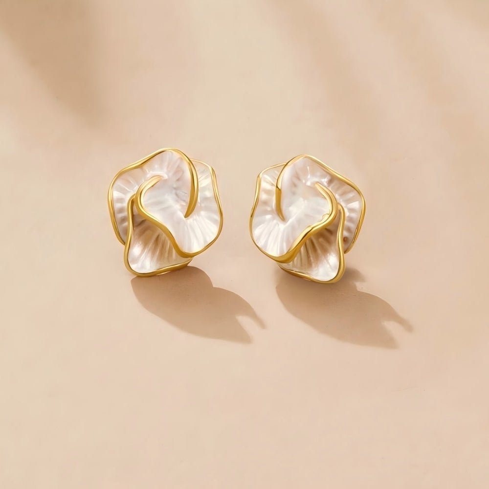 Camellia Bloom Stud Earrings, a pair of flower-shaped studs with gold rims on a beige surface