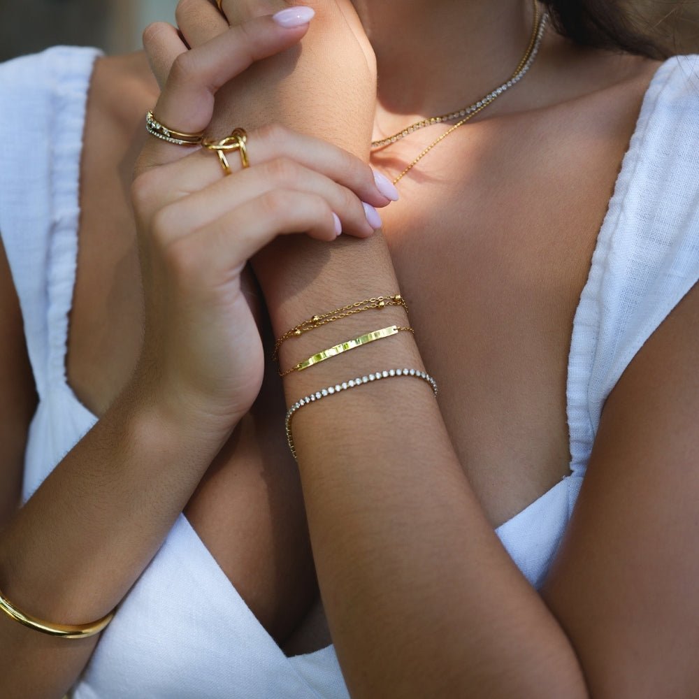 Cara Gold Bracelet, worn on a wrist with stacked gold and crystal bracelets