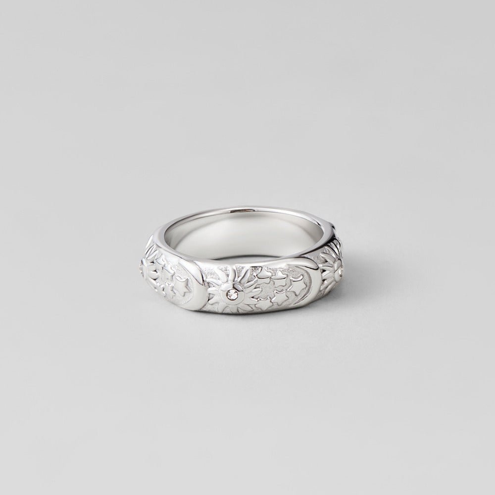 Celestial Silver Ring, standing on grey surface, wide band with moon and star relief