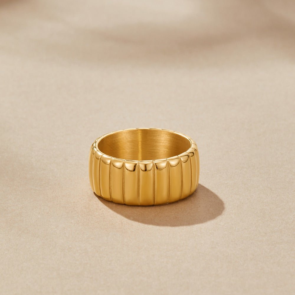 Chunky Calira Gold Ring, standing upright on beige fabric, ribbed gold band with polished ridges