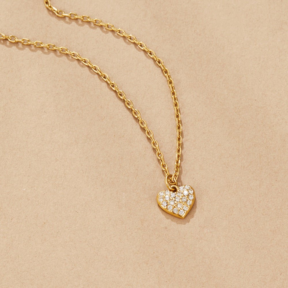 'Crazy in Love' Heart Necklace, laid flat on beige paper, gold chain with pavΓ© heart pendant