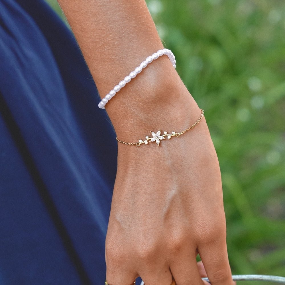 Crystal Flower Gold Bracelet, worn on a wrist with a white pearl bracelet, navy sleeve