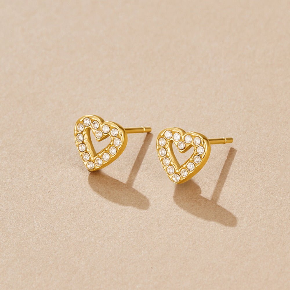 Crystal Heart Stud Earrings, pair of open heart studs on beige surface, edged with clear stones