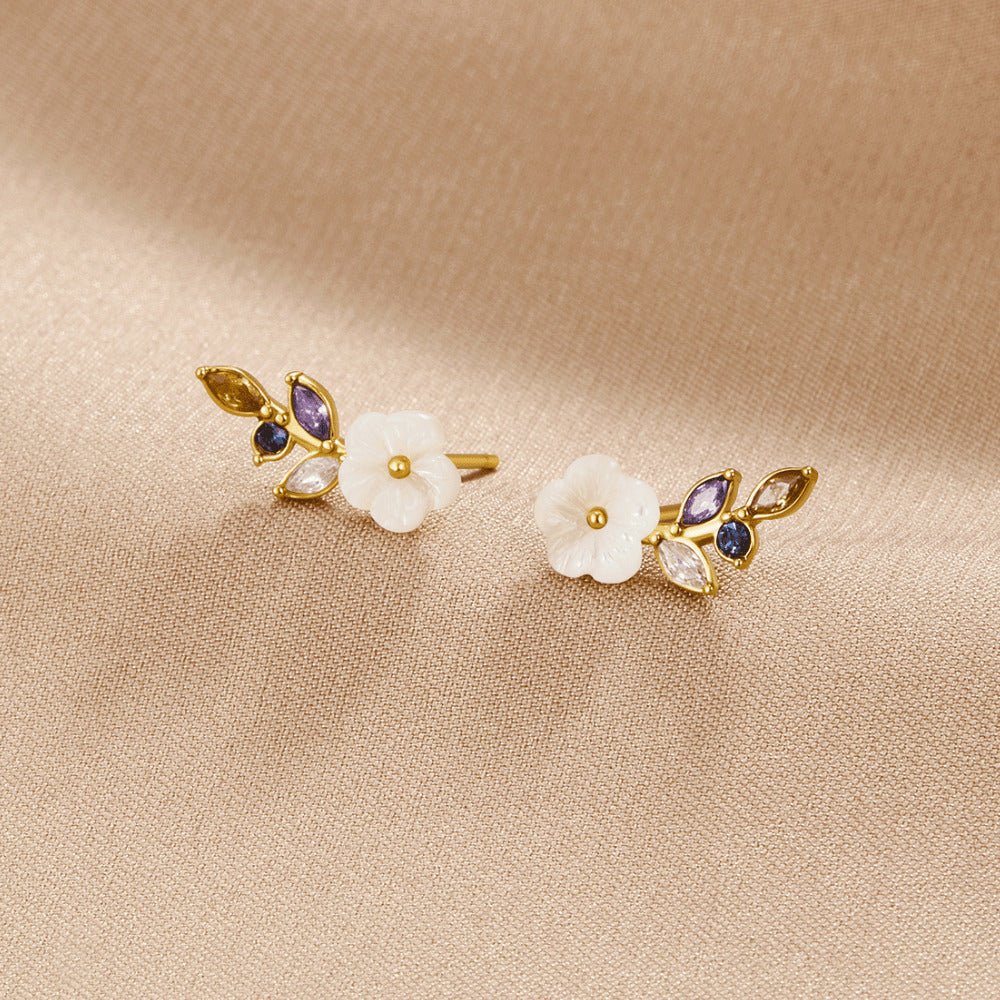 Crystal White Blossom Earrings, a pair of flower earrings lying on beige satin, with white