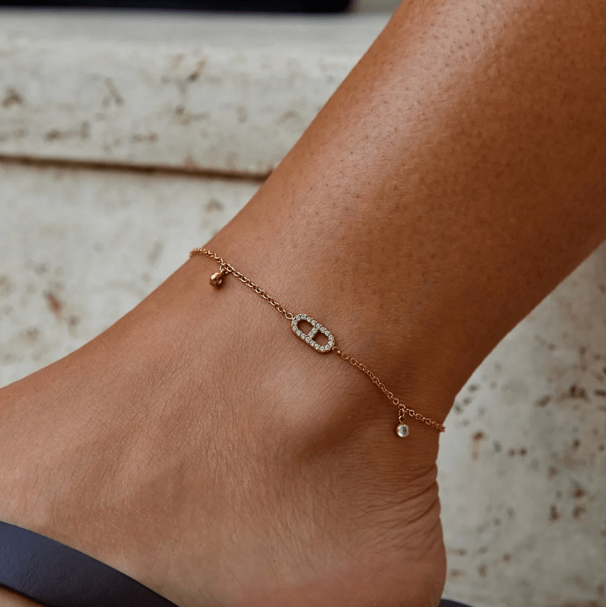 Eliza Gold Crystal Anklet, worn on an ankle with a pavΓ© oval link and dangling charms