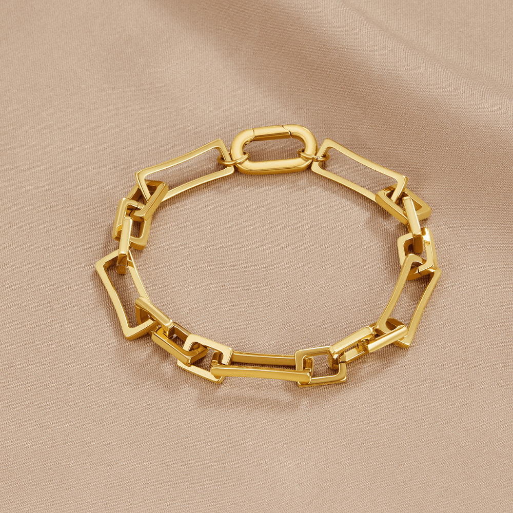 Ember Gold Chain Bracelet, laid flat on beige satin, gold rectangular link chain with clasp