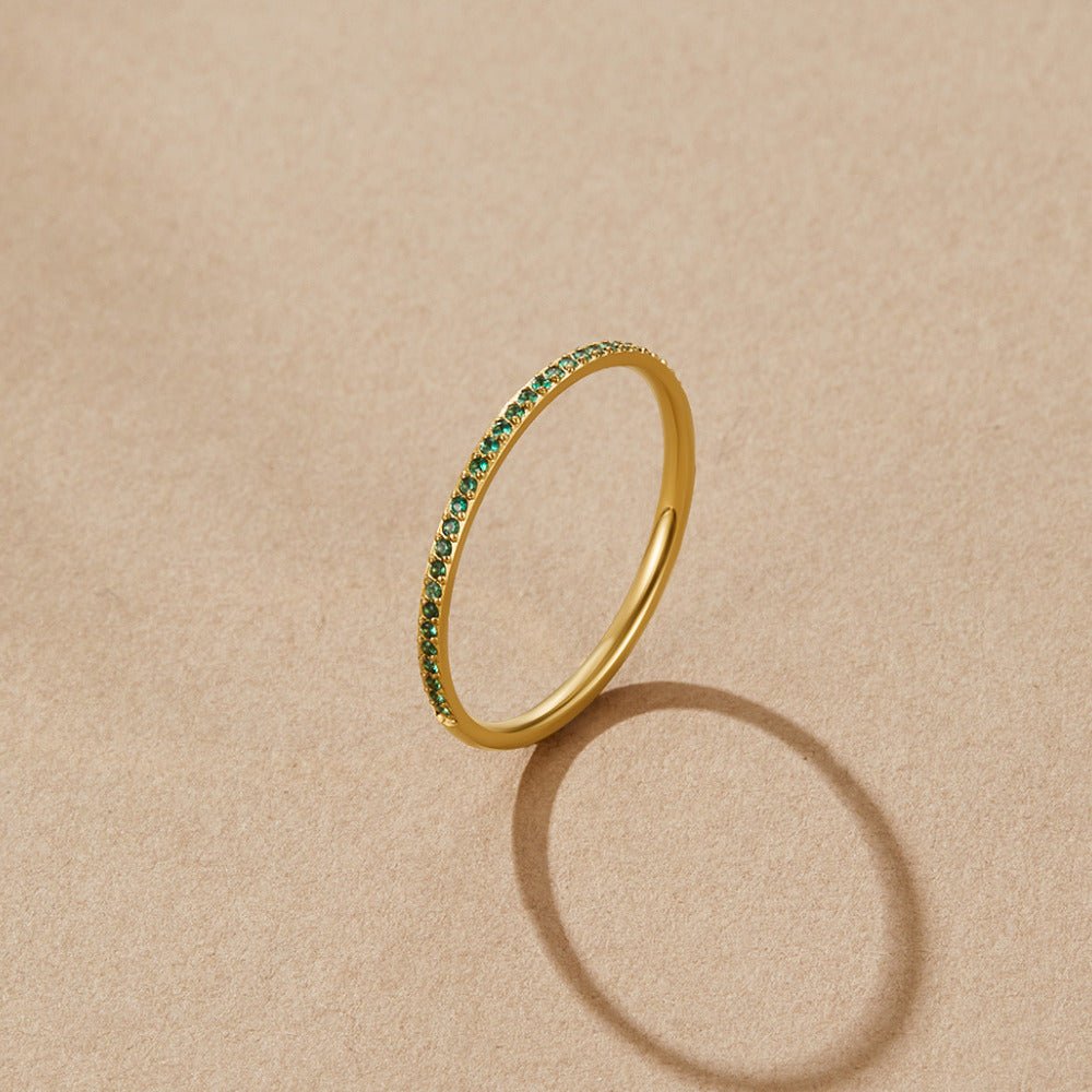Emerald Eternity Crystal Ring, standing upright on beige paper, with green stones along one side