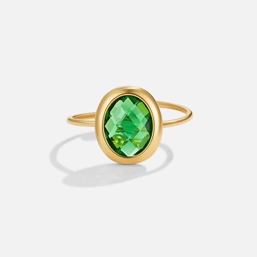 Emerald Green Crystal Gold Ring, gold ring with an oval faceted green stone, on a plain background