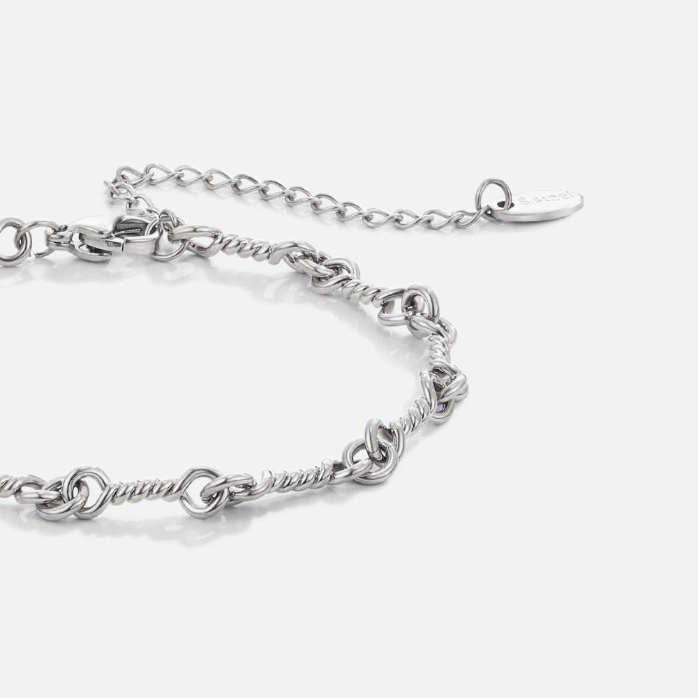 Figaro Silver Knot Chain Bracelet, lying flat on white, close-up of twisted silver links and