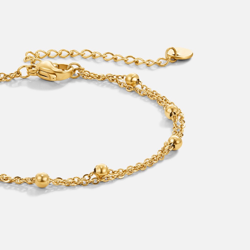 Gaia Layered Bracelet, close-up of a gold double-strand chain with round beads on white