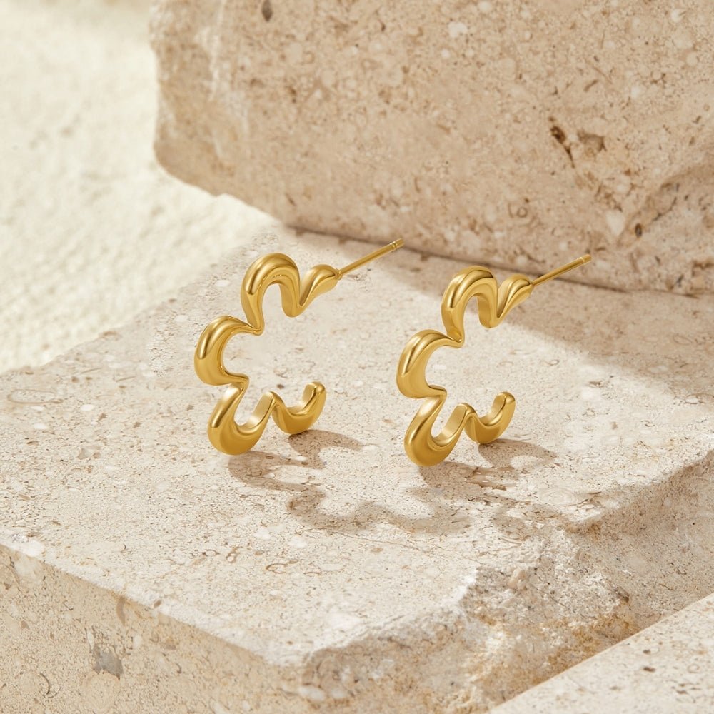 Geometric Gold Flower Hoop Earrings, a pair of earrings resting on a stone ledge in sunlight