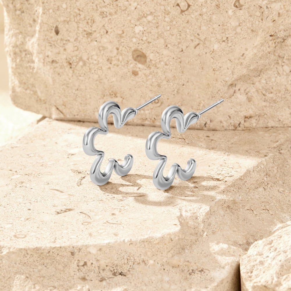 Geometric Silver Flower Hoop Earrings, a pair of silver earrings on a sandstone surface, in