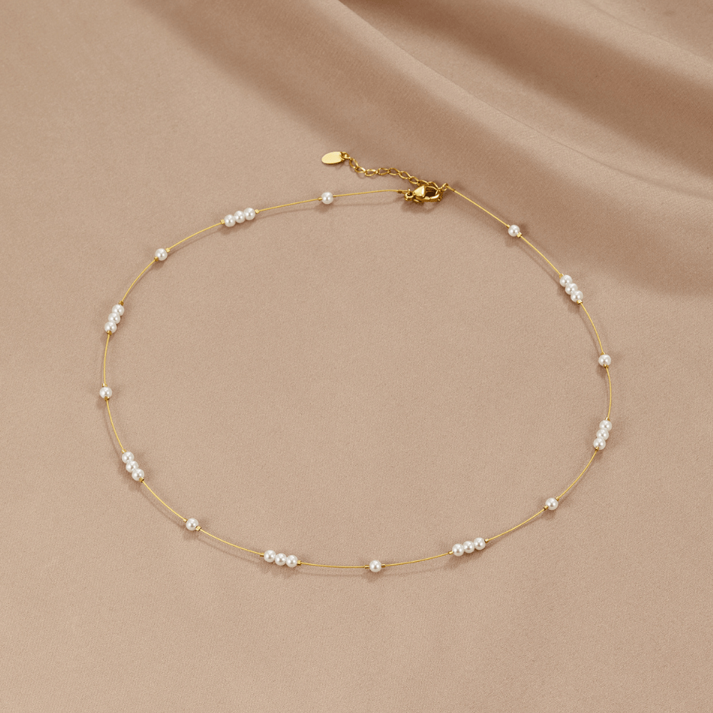 Gigi Pearl Choker Necklace, laid flat on beige satin, gold chain with small white pearls