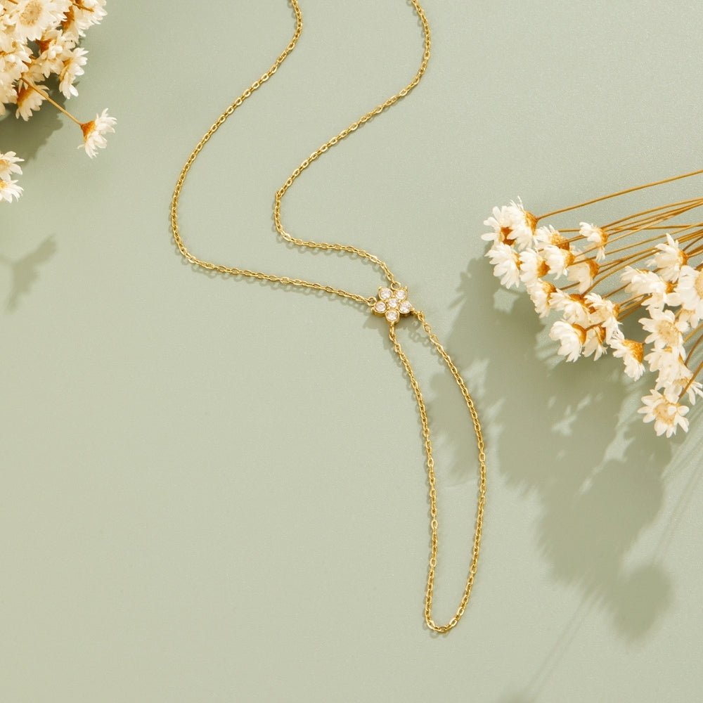 Gold & Crystal Bloom Lariat Bracelet, laid flat on sage green with dried white flowers