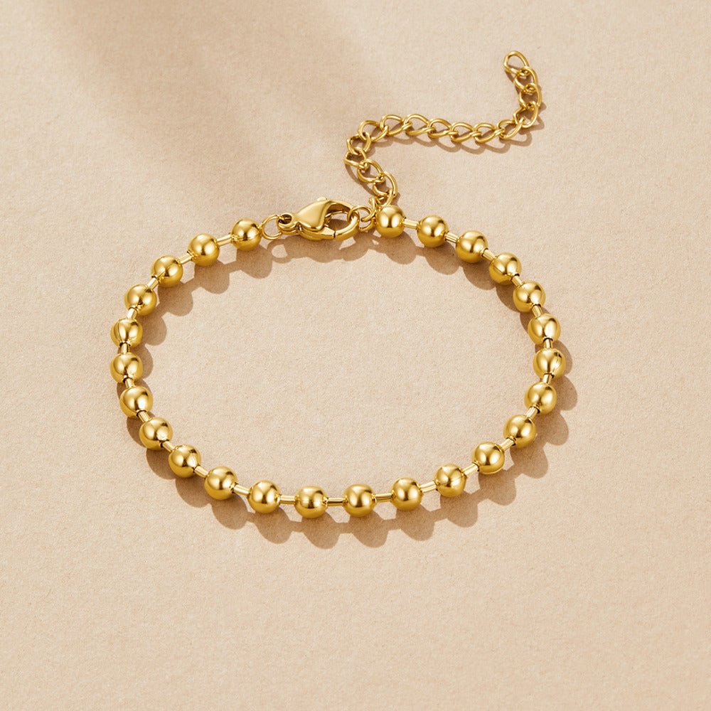 Gold Lulu Bead Bracelet, laid flat on beige fabric, with gold beads and a lobster clasp