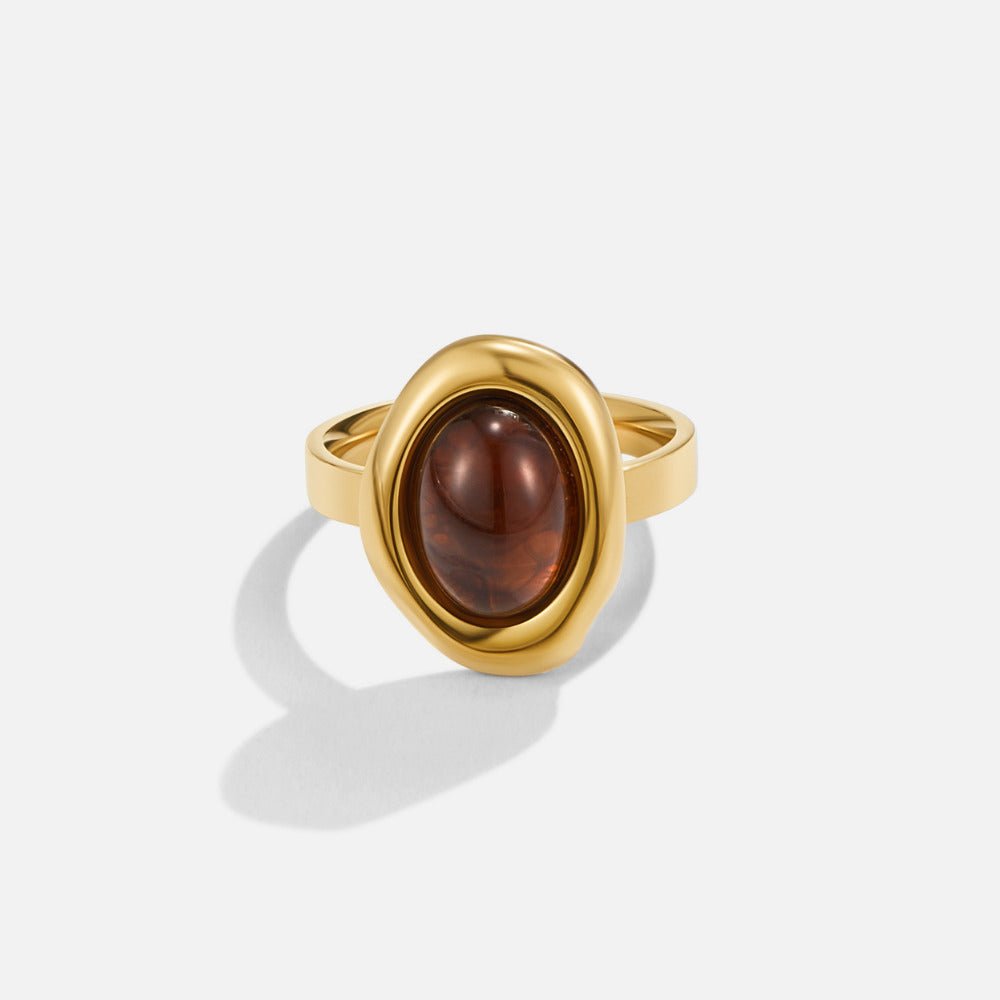 Golden Amber Ring, ring on a plain white background, gold band with oval brown cabochon