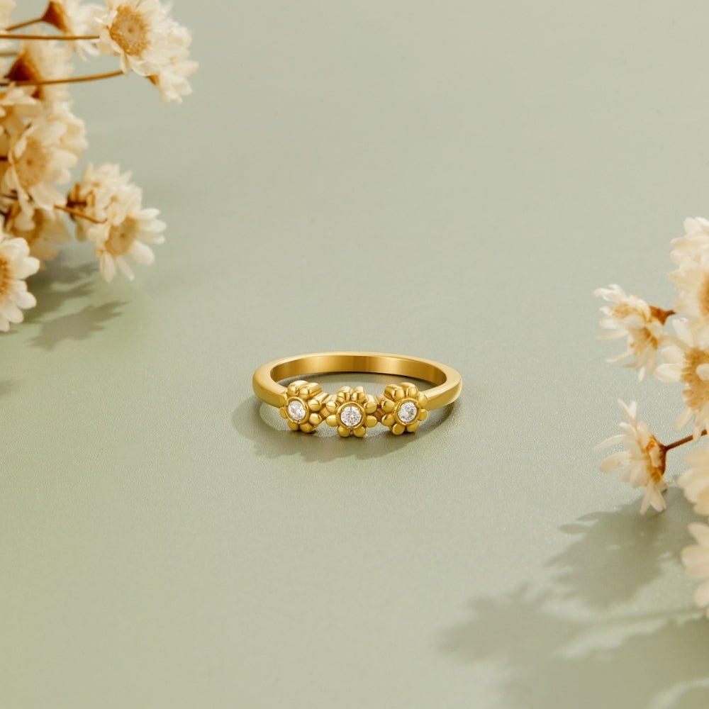 Golden Daisy Infinity Ring, gold ring with three daisy motifs on a sage backdrop