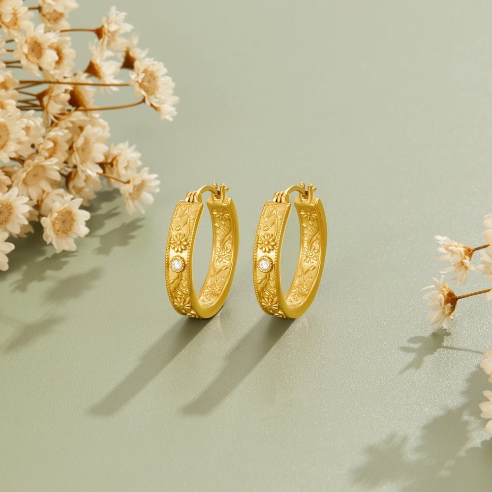 Golden Sculpted Flower Hoop Earrings, pair of gold hoop earrings on sage surface with dried