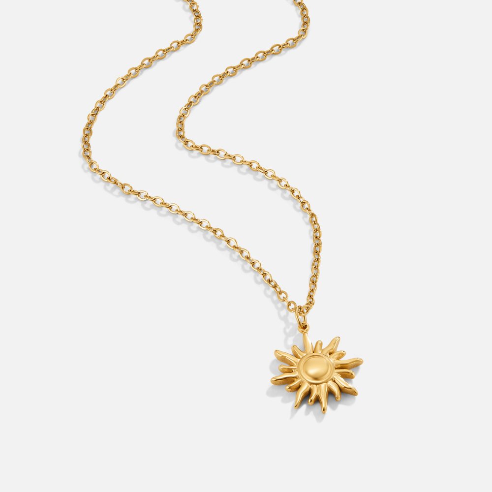 Golden Sunburst Necklace, lying flat on white, gold chain with sun-shaped pendant
