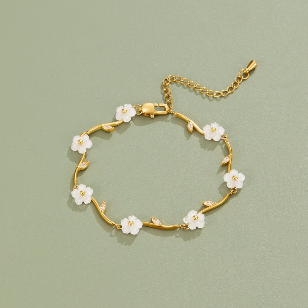 Golden White Pearl Blossom Bracelet, gold bracelet laid flat on sage green with white flower charms