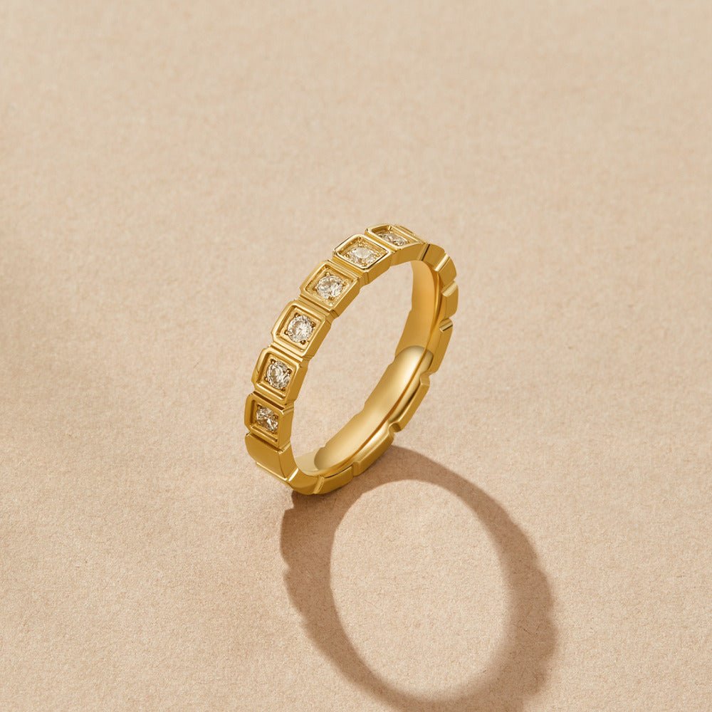 Hera Gold Crystal Ring, standing upright on beige paper, casting a shadow; gold with clear stones