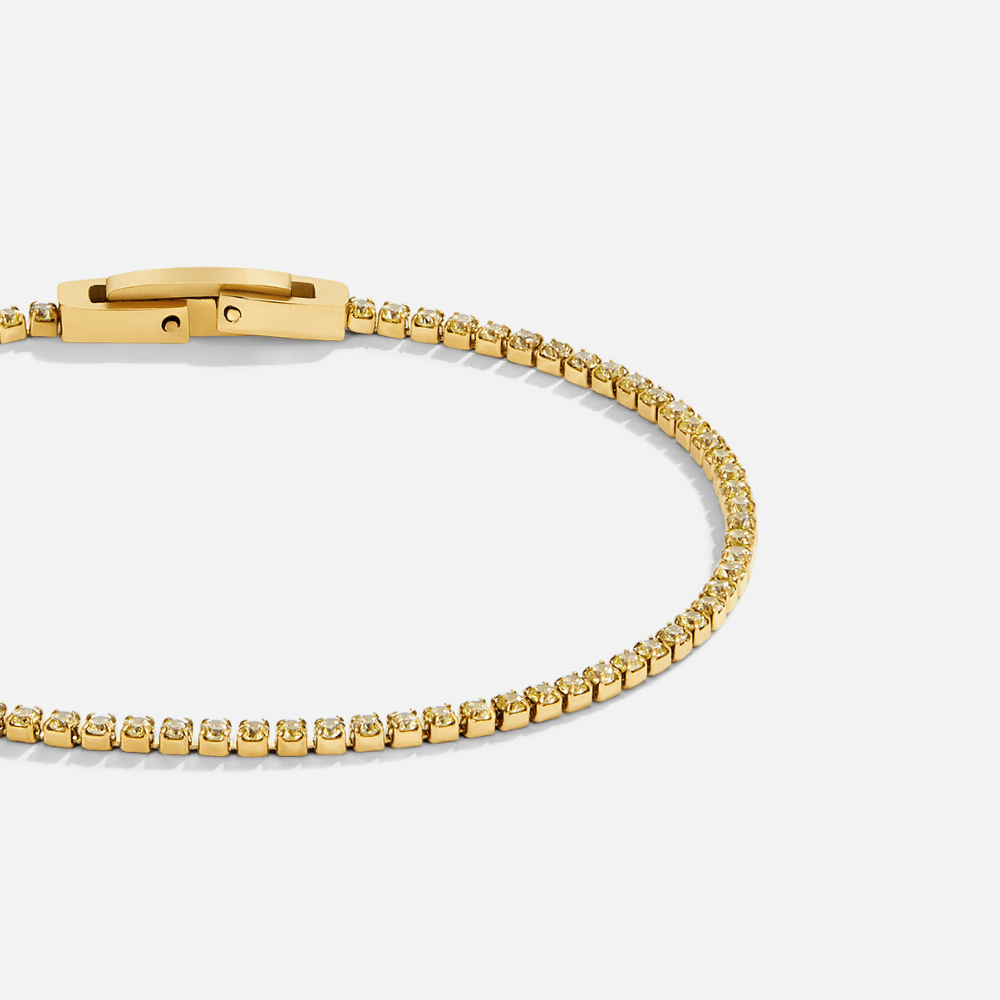 Keana Peridot Crystal Bracelet, laid in a loop on a plain light background, gold clasp at top-left