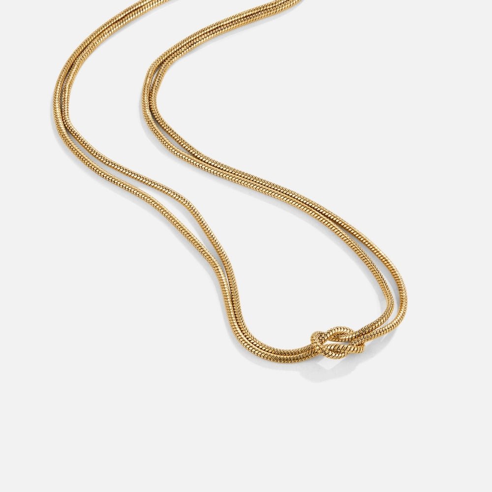 Knotted Gold Chain Necklace, lying flat on white, two gold chains tied in a knot