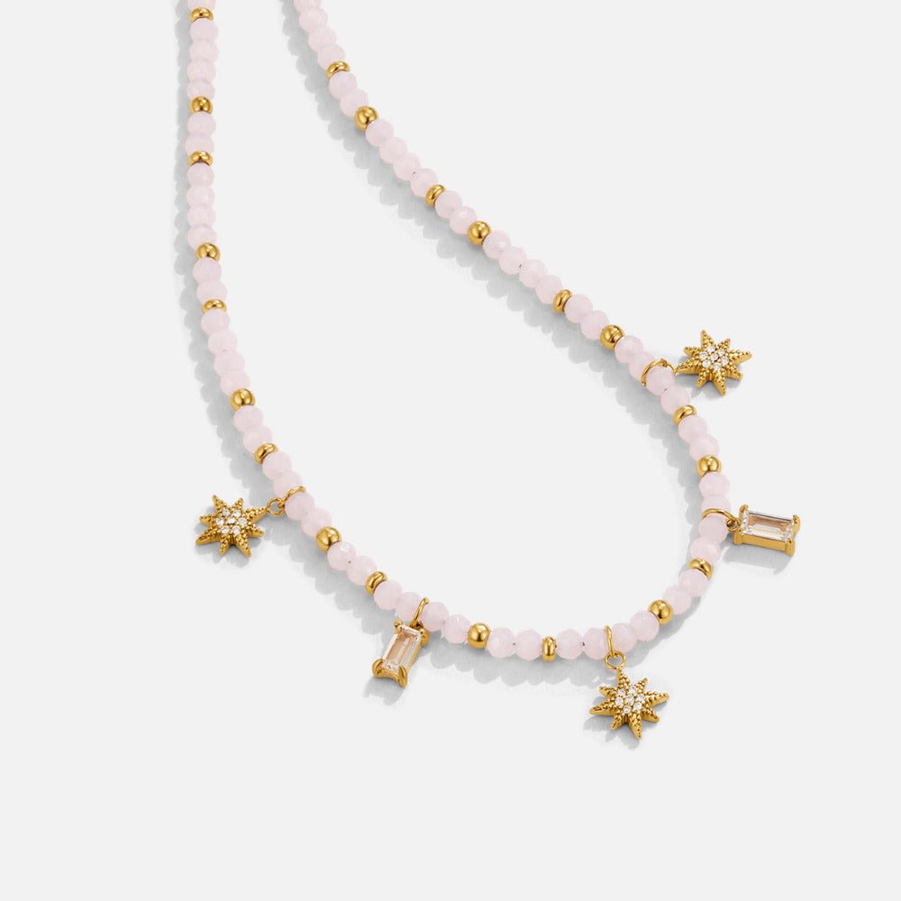 Lana Pink Bead Necklace, laid flat on a light grey surface, pink beads with gold charms