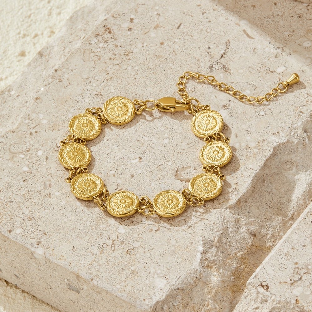Lara Gold Medallion Bracelet, laid flat on pale stone, gold disc medallions with sunburst