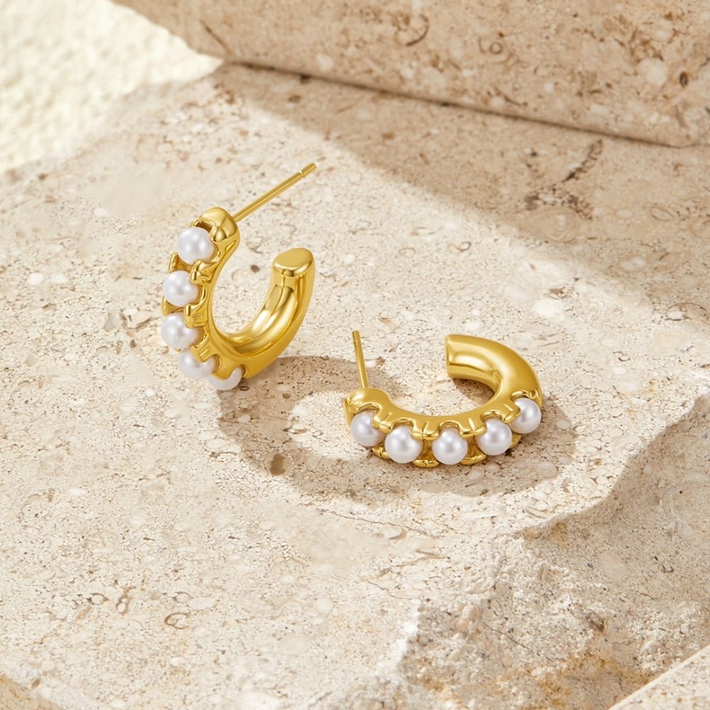 Lena Pearl Gold Hoop Earrings, pair of gold hoops with pearls, resting on textured stone