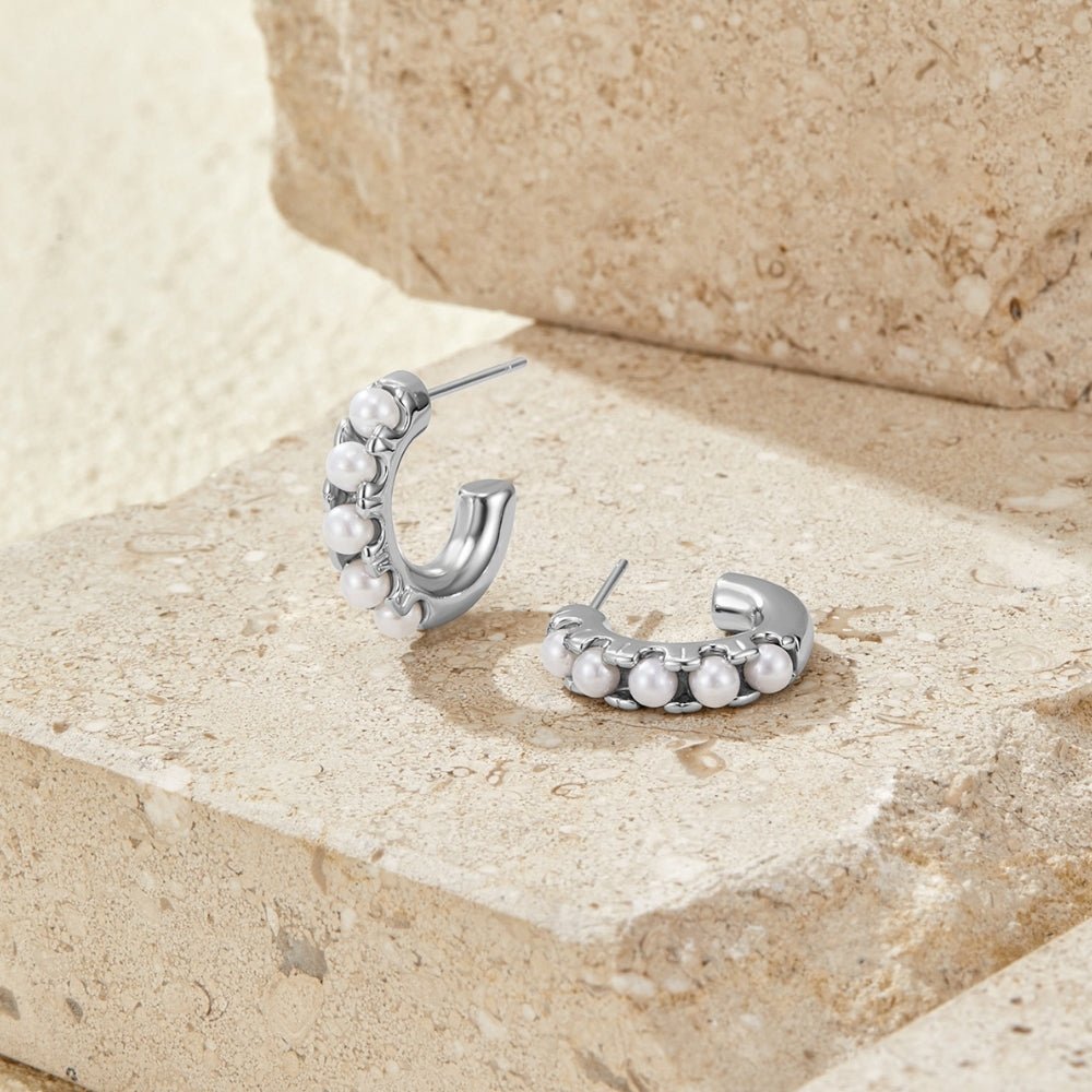 Lena Pearl Silver Hoop Earrings, a pair of silver hoops with pearls, resting on beige stone