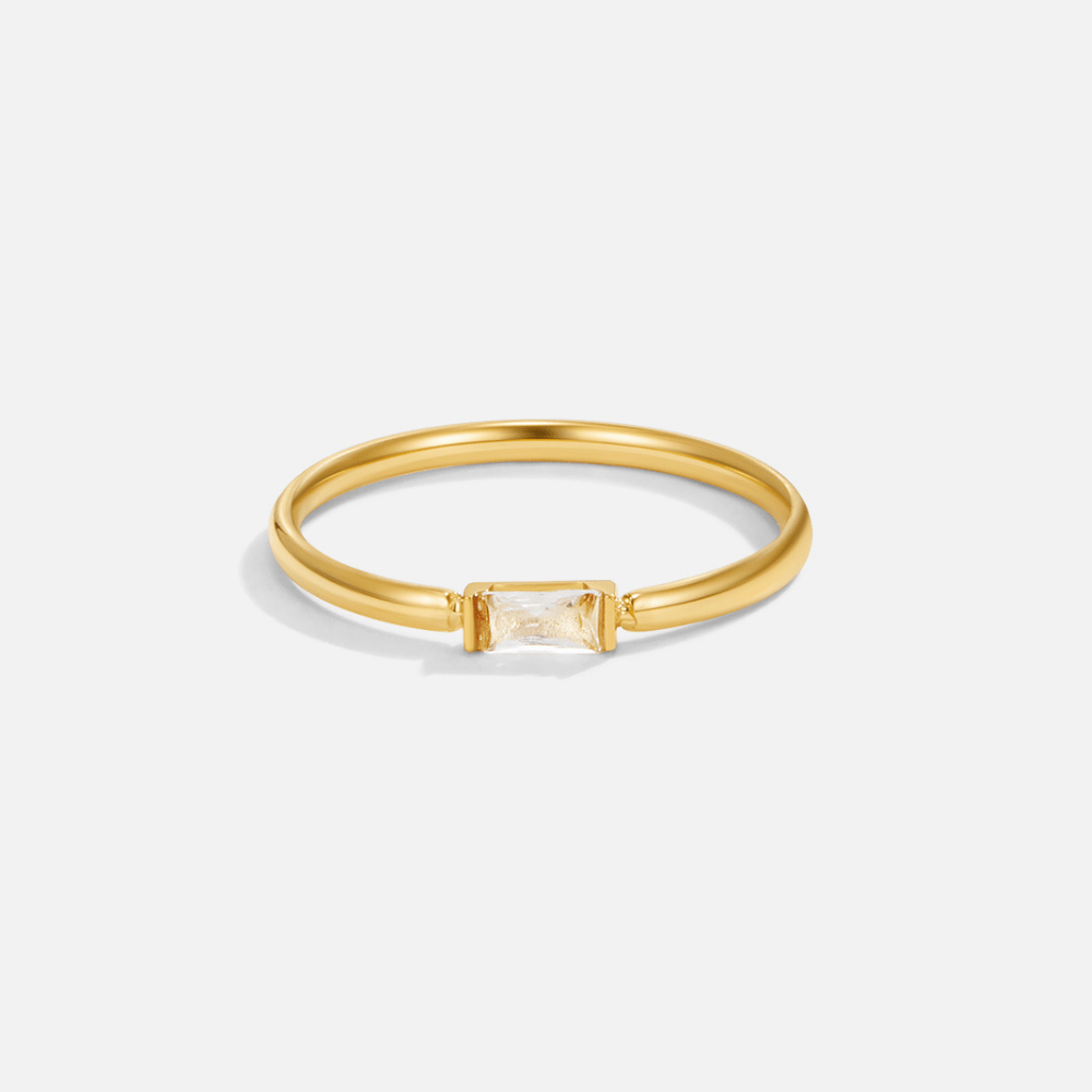 Leonore Baguette Crystal Ring, gold band ring on white background with rectangular clear crystal